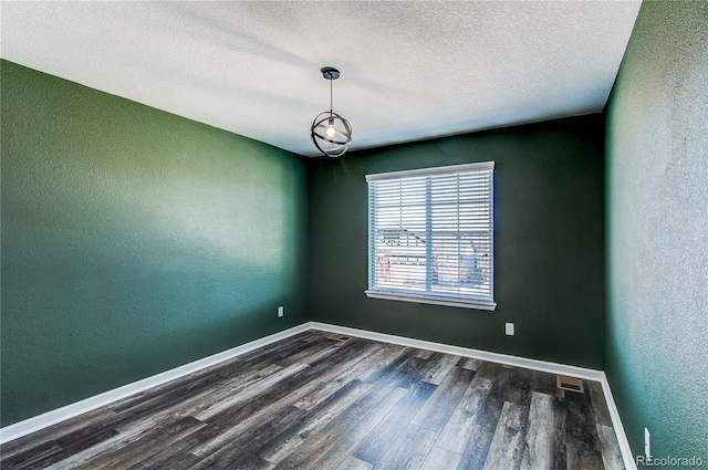 unfurnished room with dark wood-type flooring and a textured ceiling