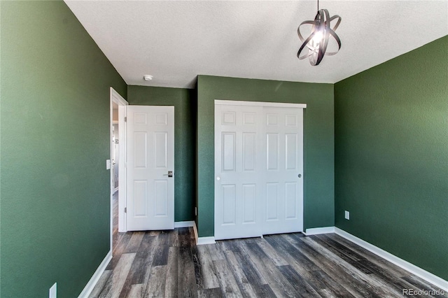 unfurnished bedroom with a textured ceiling, dark hardwood / wood-style flooring, and a closet