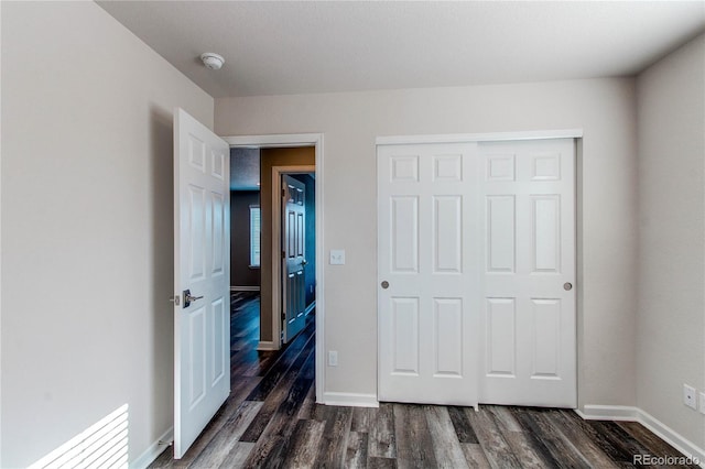 unfurnished bedroom with a closet and dark hardwood / wood-style floors