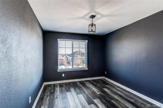 empty room with dark hardwood / wood-style floors and a textured ceiling