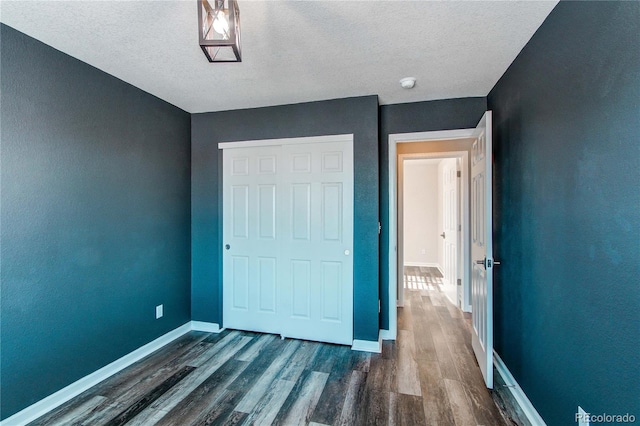 unfurnished bedroom with dark wood-type flooring and a textured ceiling