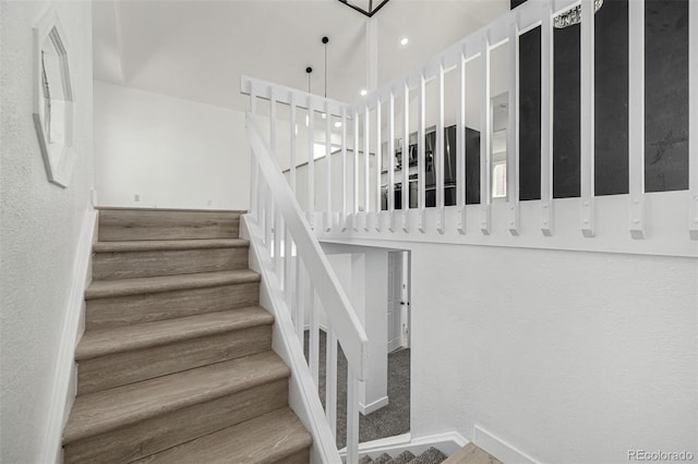 staircase featuring a high ceiling and baseboards