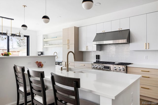 kitchen with a breakfast bar area, backsplash, white cabinets, pendant lighting, and stove