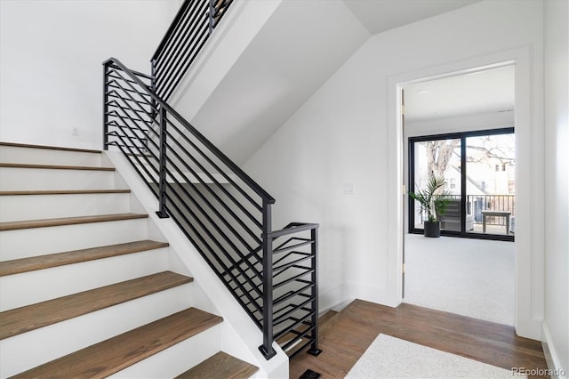 staircase with wood-type flooring and vaulted ceiling