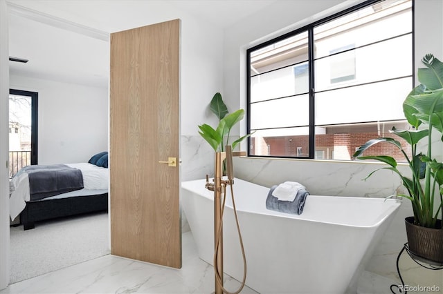 bathroom with connected bathroom, a freestanding bath, a wealth of natural light, and marble finish floor