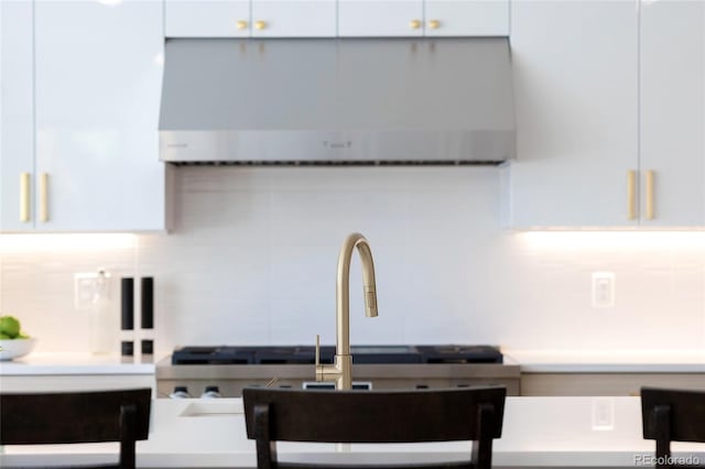 kitchen with backsplash, white cabinets, and range hood