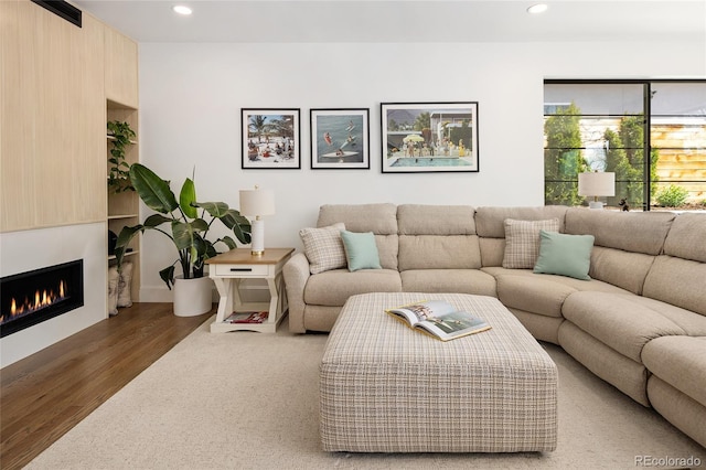 living area with recessed lighting, a large fireplace, and wood finished floors