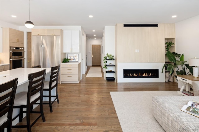 living room featuring a lit fireplace, recessed lighting, wood finished floors, and visible vents