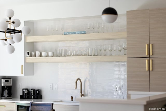 kitchen featuring a sink, light countertops, beverage cooler, decorative backsplash, and modern cabinets