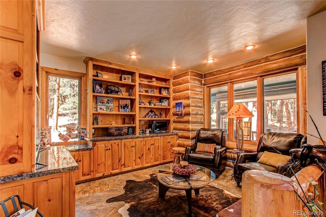 living room with log walls and a textured ceiling