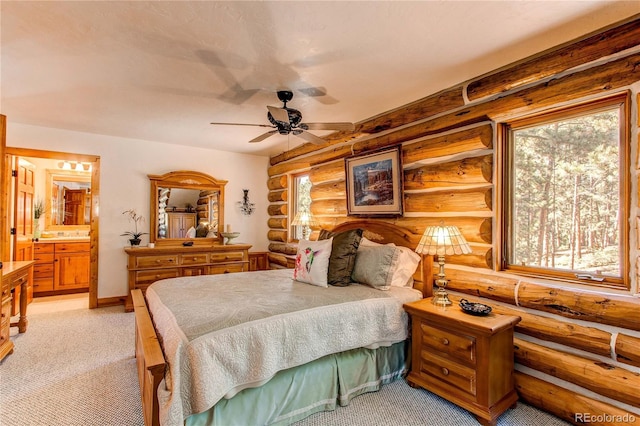 bedroom featuring ensuite bathroom, log walls, light carpet, and ceiling fan