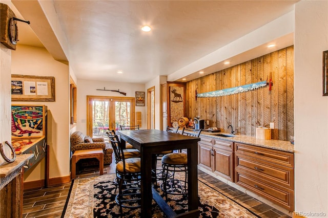 dining room with dark hardwood / wood-style floors, wood walls, and sink