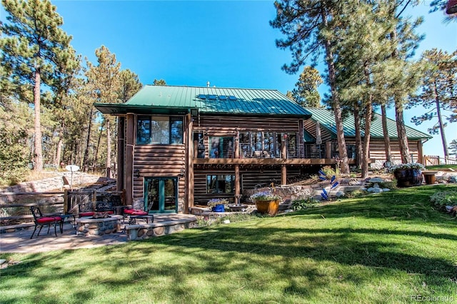 rear view of property featuring a lawn, a patio area, a fire pit, and a deck