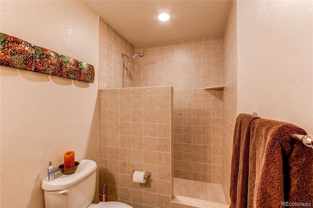 bathroom with tiled shower and toilet