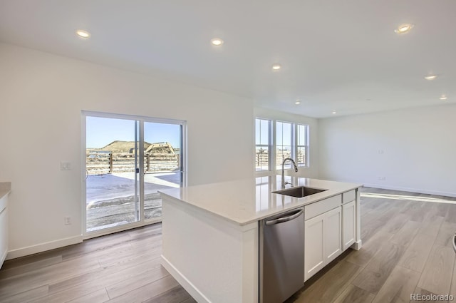 kitchen featuring white cabinetry, sink, stainless steel dishwasher, a kitchen island with sink, and light wood-type flooring