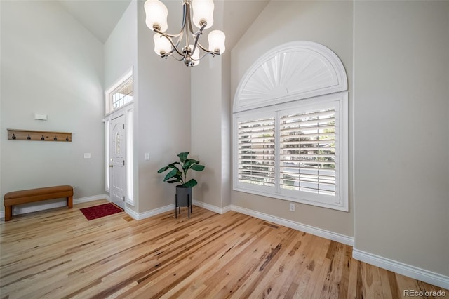 foyer featuring a healthy amount of sunlight, light hardwood / wood-style floors, high vaulted ceiling, and a notable chandelier