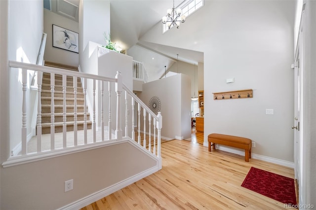 entryway featuring high vaulted ceiling, a wealth of natural light, hardwood / wood-style flooring, and a chandelier