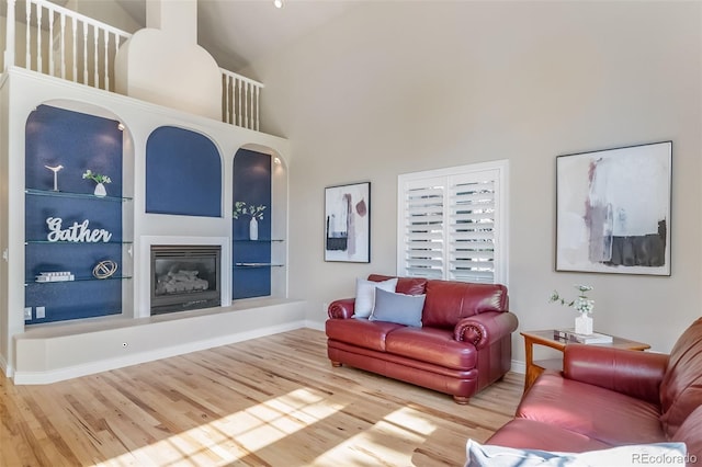 living room with a towering ceiling, hardwood / wood-style flooring, and built in shelves