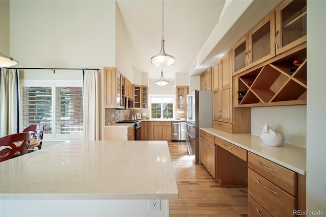 kitchen with a wealth of natural light, pendant lighting, stainless steel appliances, and tasteful backsplash