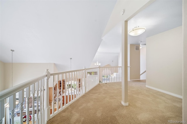 hallway featuring light colored carpet, a chandelier, and vaulted ceiling