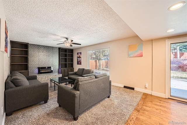 living room with ceiling fan, a tile fireplace, wood-type flooring, and a wealth of natural light