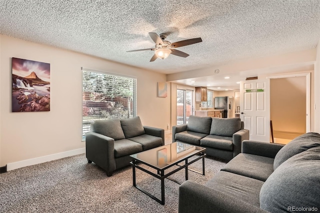 living room featuring ceiling fan, carpet floors, and a textured ceiling