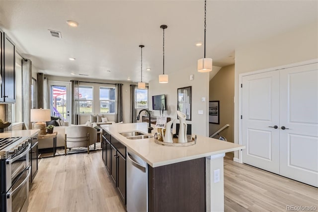 kitchen with pendant lighting, sink, light hardwood / wood-style flooring, a center island with sink, and appliances with stainless steel finishes