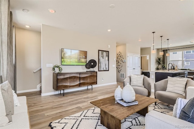 living room with light hardwood / wood-style flooring and sink