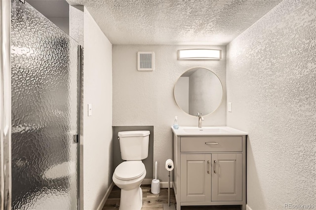 bathroom featuring vanity, wood-type flooring, a shower with door, and a textured ceiling