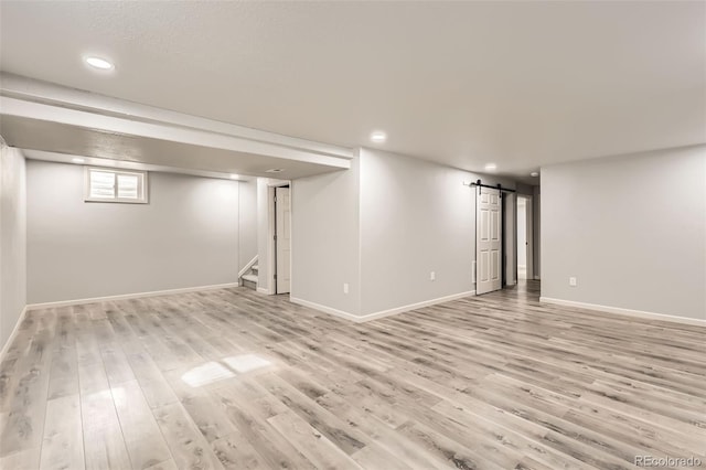 basement featuring a barn door and light wood-type flooring