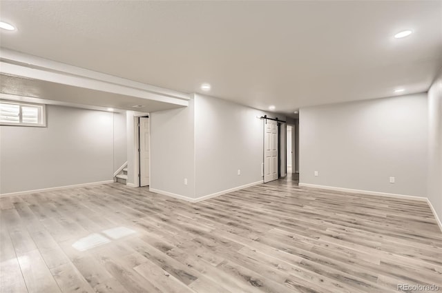 basement featuring a barn door and light wood-type flooring