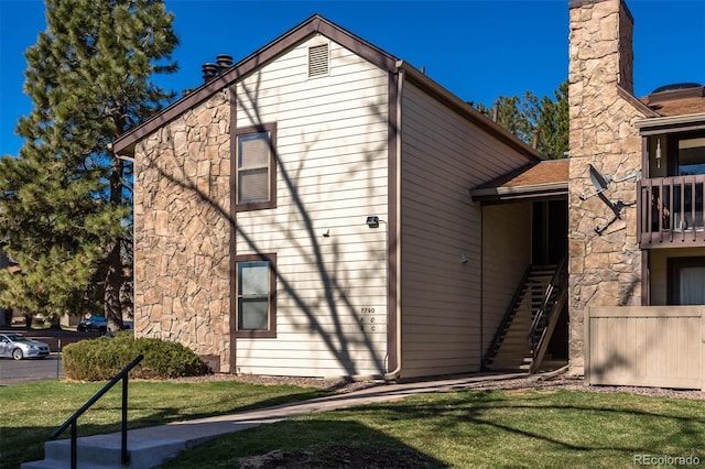 view of side of property with stairway, a lawn, and stone siding