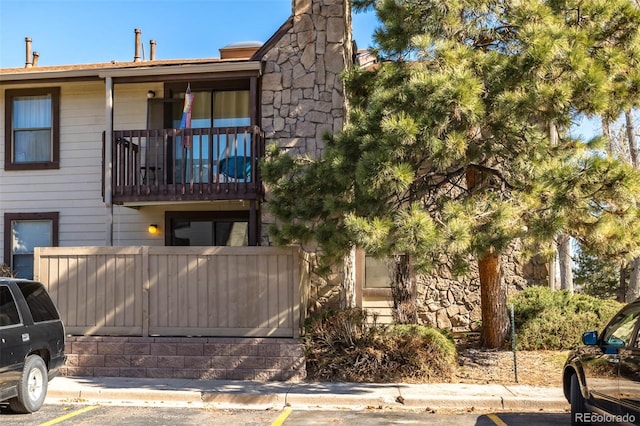 view of front of home with a balcony, uncovered parking, and fence