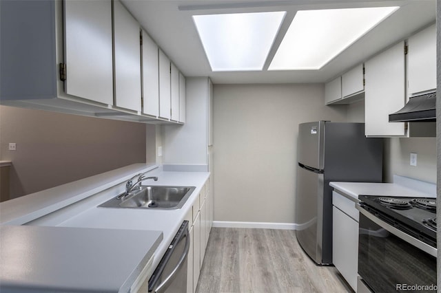 kitchen featuring under cabinet range hood, a sink, stainless steel appliances, light wood-style floors, and light countertops