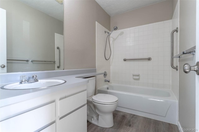 bathroom with toilet, vanity, bathtub / shower combination, wood finished floors, and a textured ceiling