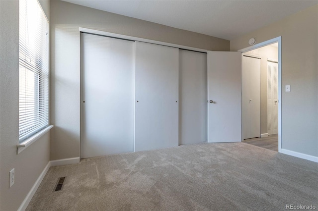 unfurnished bedroom with a closet, baseboards, carpet, and visible vents