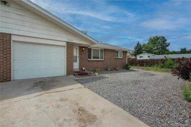 single story home with a garage, fence, concrete driveway, and brick siding