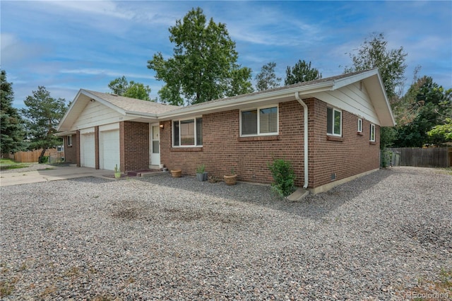 ranch-style home featuring a garage, concrete driveway, brick siding, and fence