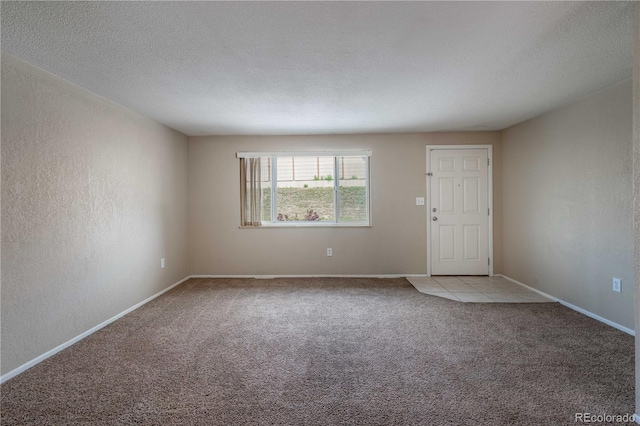 unfurnished room featuring carpet flooring, a textured wall, a textured ceiling, and baseboards