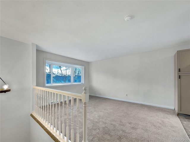 spare room featuring baseboards and light colored carpet