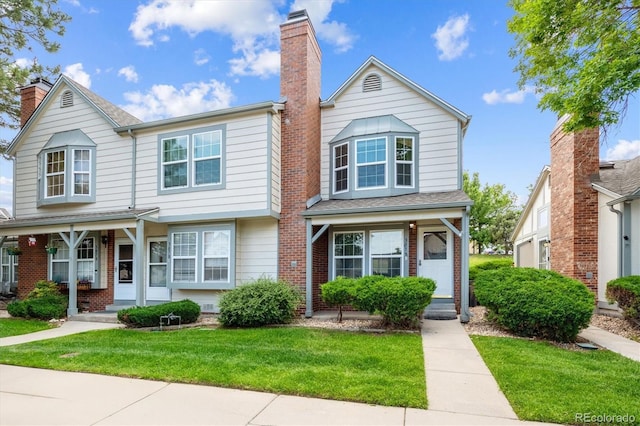 3078 W 107th Pl Unit D, Westminster, CO 80031 - view of front of home with a front lawn, a chimney, covered porch, and brick siding