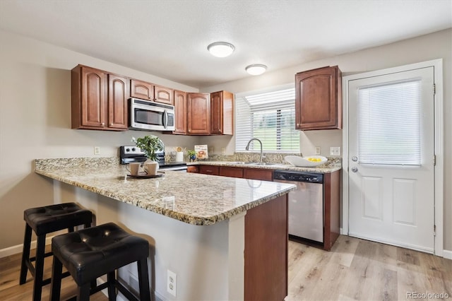 3078 W 107th Pl Unit D, Westminster, CO 80031 - kitchen with stainless steel appliances, a peninsula, light wood-style flooring, and a breakfast bar