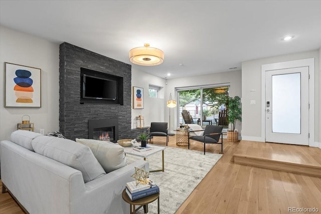 living room featuring hardwood / wood-style flooring and a stone fireplace