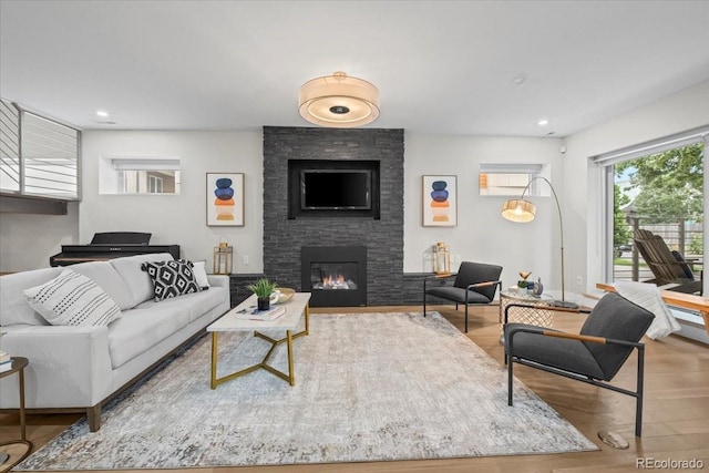 living room with wood-type flooring and a stone fireplace