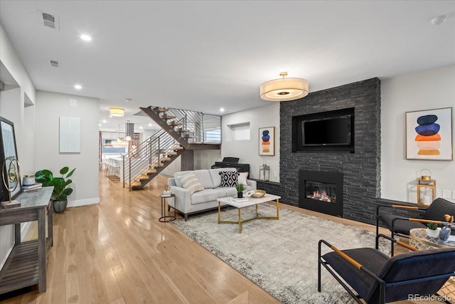 living room with a stone fireplace and light wood-type flooring