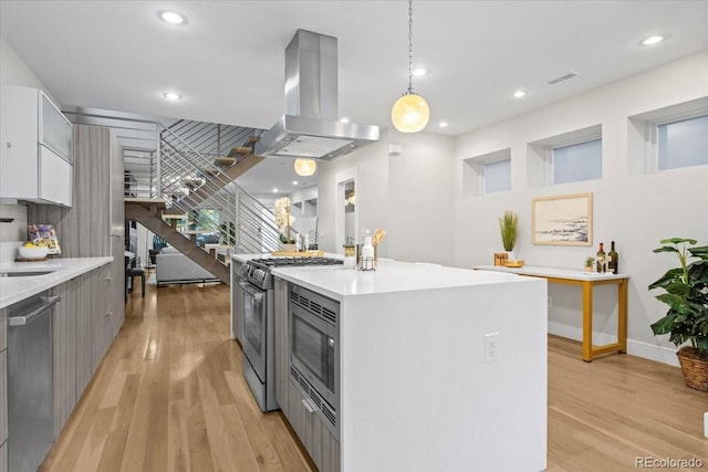 kitchen with gray cabinets, stainless steel appliances, a center island, island exhaust hood, and decorative light fixtures