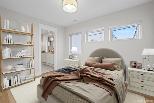 bedroom with ensuite bath and light wood-type flooring