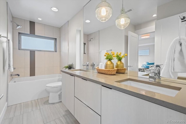 full bathroom featuring vanity, tiled shower / bath, and toilet