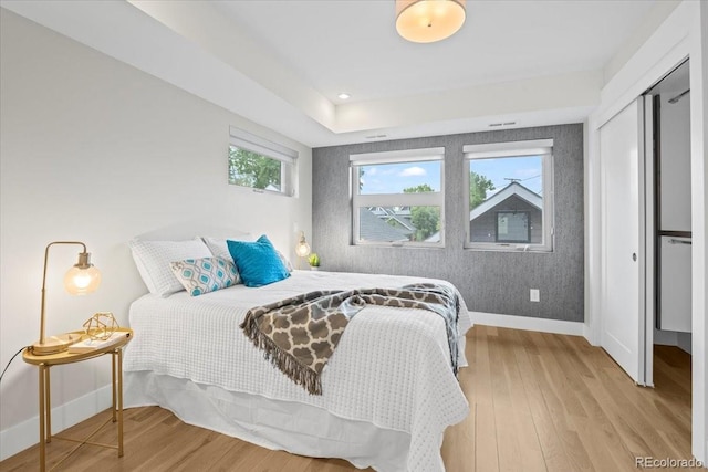 bedroom featuring multiple windows, light hardwood / wood-style floors, and a closet