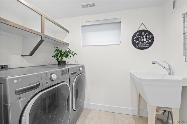 clothes washing area featuring separate washer and dryer, sink, and light tile patterned flooring